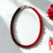 Handmade Crimson Noir Kumihimo beaded necklace with red and black glass seed beads styled with roses on white background